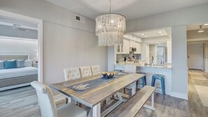 Une cuisine moderne avec des meubles blancs, un îlot central et un luminaire suspendu.