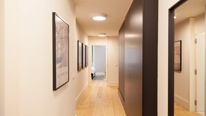 A hallway with framed artwork on the walls, a wooden floor, and a door at the end.