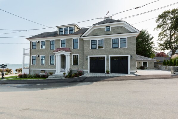 A two-story house with a garage, a front porch, and a view of the water.
