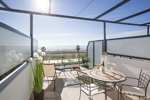 Enjoy the ocean view from this balcony with a table and chairs, perfect for relaxing with a potted plant nearby.