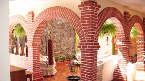 Un patio con arcos de ladrillo, un muro de piedra y plantas en macetas.