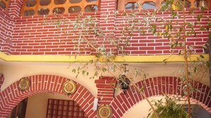 Un edificio de ladrillo rojo con detalles en amarillo, con ventanas arqueadas y placas decorativas.