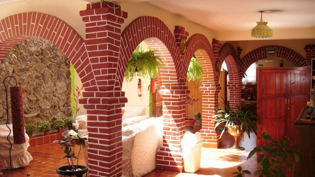 Un interior espacioso con arcos de ladrillo, pared de piedra y plantas en macetas.