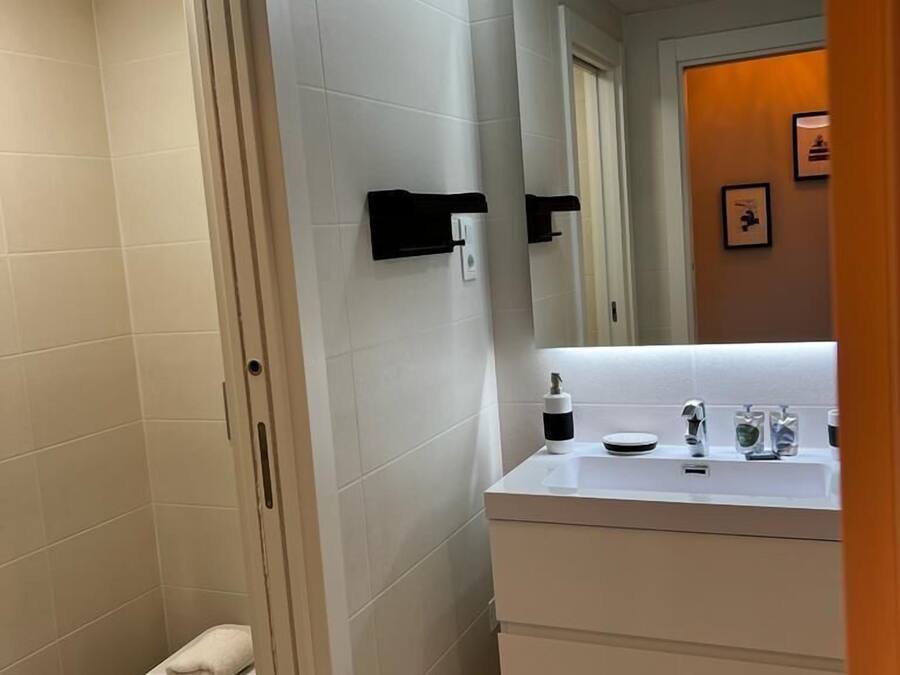 Une salle de bain moderne avec un lavabo blanc, un miroir et des toilettes.