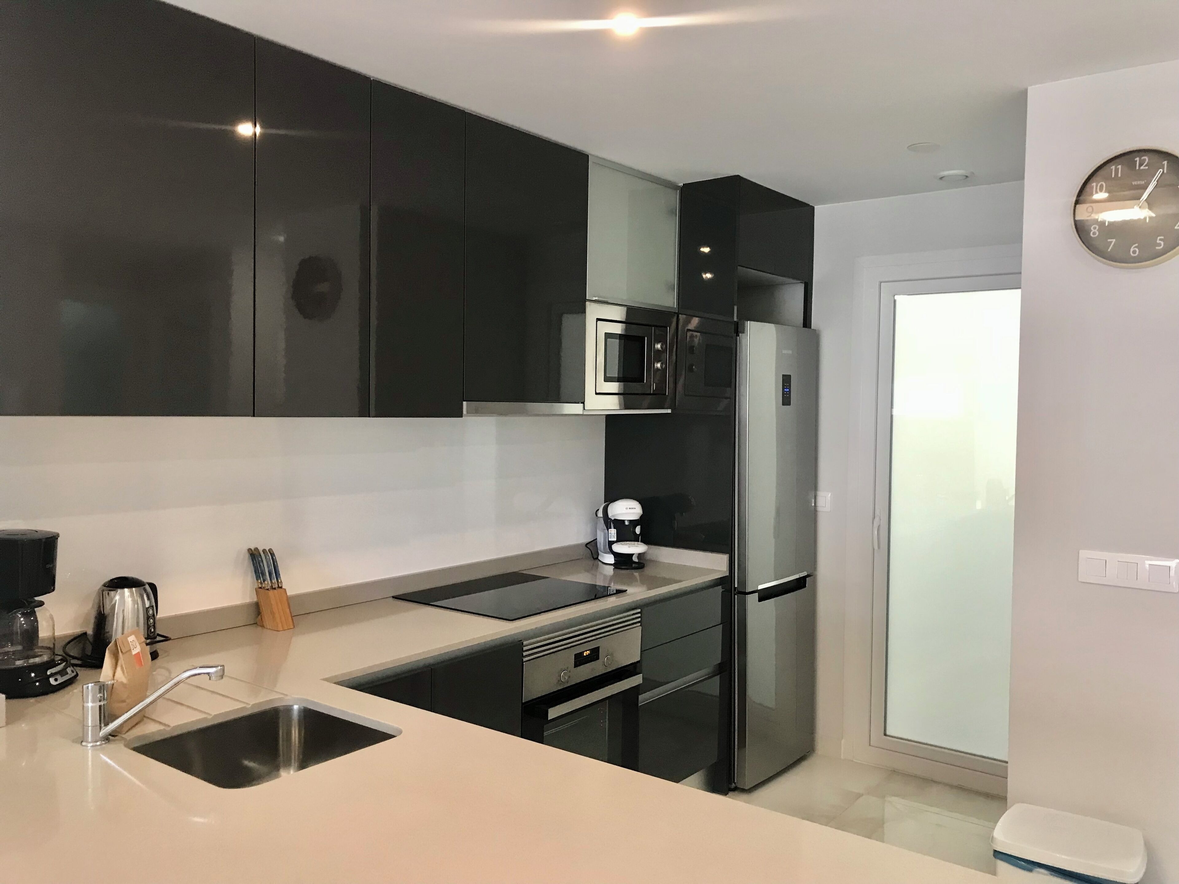 A modern kitchen with a stainless steel refrigerator, a microwave, and a sink.