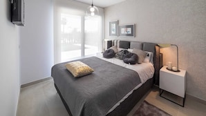 Een moderne slaapkamer met een groot bed, een nachtkastje met een lamp, en uitzicht op het landschap door een groot raam.