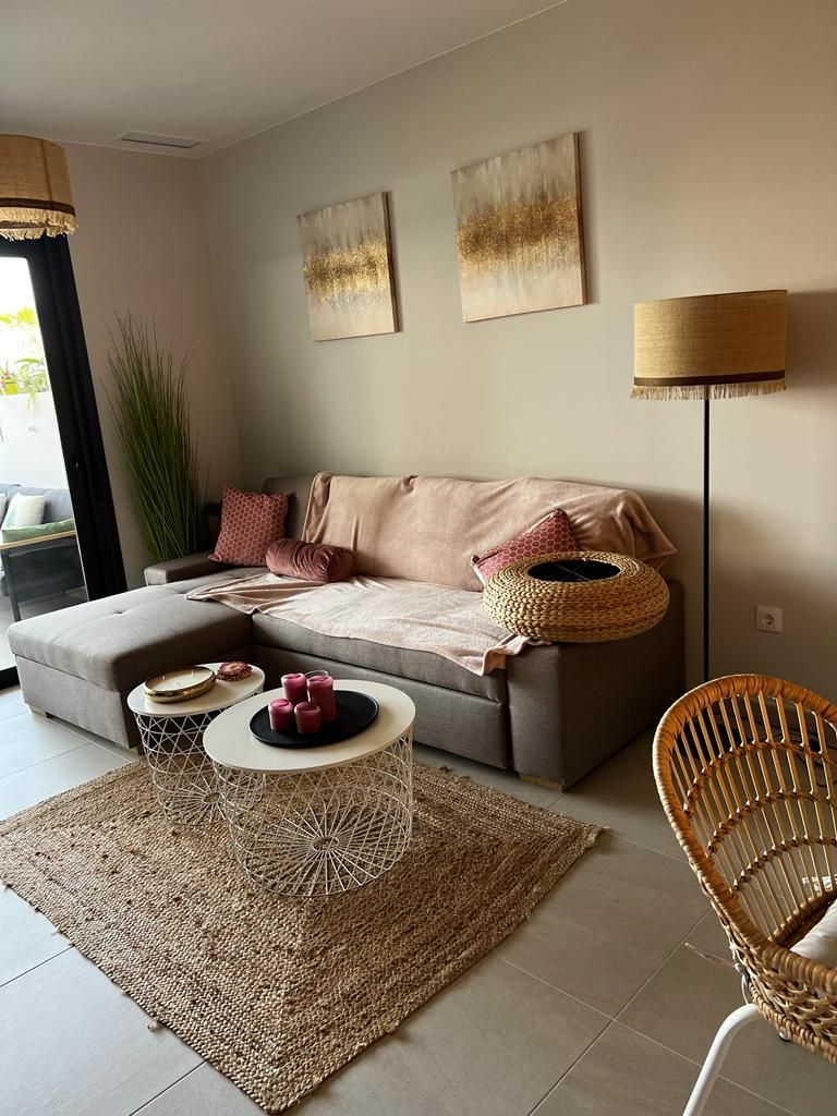 A modern living room with a grey sofa, a round coffee table, a wicker chair, and a floor lamp.