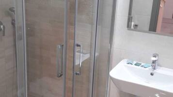A modern bathroom with a glass-enclosed shower, a white sink, and a mirror above it.
