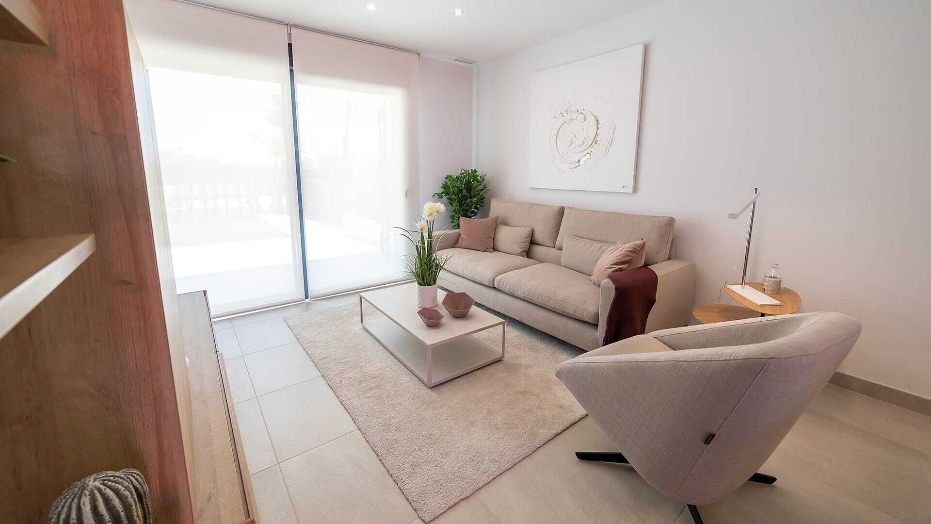 Una sala de estar moderna con un sofá, una mesa de centro y una silla. Hay una planta sobre la mesa de centro y un cuadro en la pared.