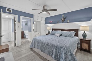 Une chambre à coucher avec un grand lit, un ventilateur de plafond et une table de chevet avec une lampe.