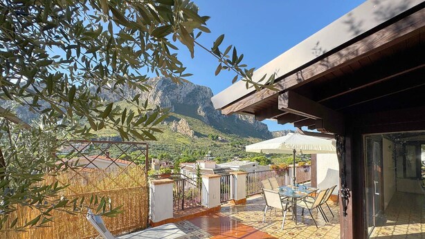 A patio with outdoor furniture, a view of a mountain, and a building with a tiled floor. - Solemar Sicilia - Seaside House (Santa Flavia)
