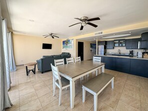 A modern apartment with a dining area, kitchen, living room, and two ceiling fans. - Find Peace at a Modern Ground Floor Condo #107 (Puerto Peñasco)
