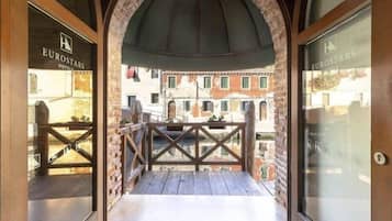 Vista desde el balcón de un hotel Eurostars, con un arco de ladrillo, barandilla de madera y una pincelada del paisaje urbano.