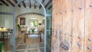 Un intérieur rustique avec un sol en pierre, des poutres en bois et une porte vitrée donnant sur un patio.