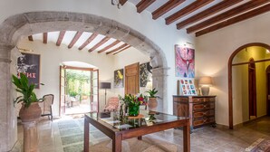 Un vaste espace de vie agrémenté d’une table basse en verre, d’une cheminée en pierre et offrant une vue sur un jardin, accessible par une arche.
