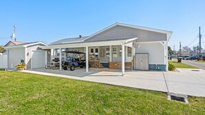 A single-story house with a covered porch, a garage, and a small lawn. - Free Golf Cart, Beach Access/w Parking, + 3 pools! (Surfside Beach)