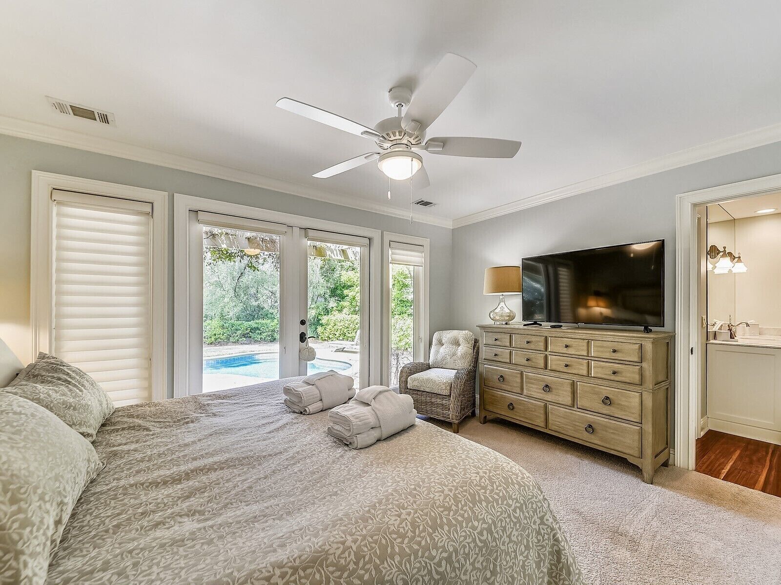 A bedroom with a bed, a dresser, a television, and a ceiling fan.