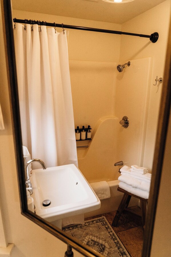 A bathroom with a shower, sink, and a towel rack.