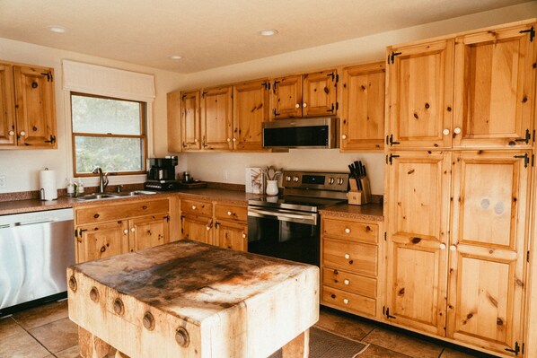 Une cuisine avec des meubles en bois, un four à micro-ondes en acier inoxydable, une cuisinière et un lave-vaisselle.