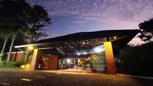 A building entrance with a covered walkway, brick walls, and potted plants.