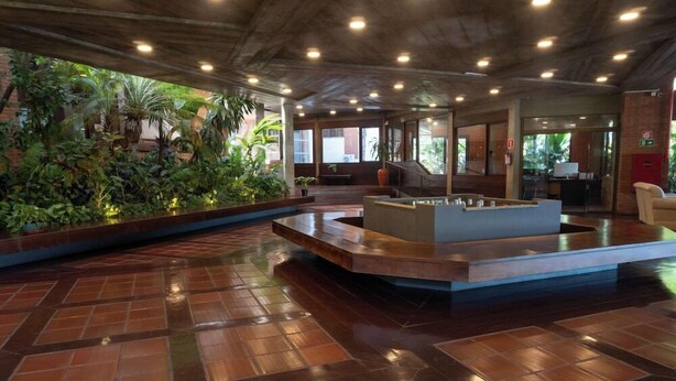 A lobby with a central seating area, a staircase, and a view of the outdoors.