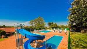 A pool area with two blue slides, sun loungers, and umbrellas.