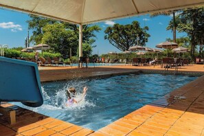A swimming pool area with a covered seating area and umbrellas. - Hotel Colonial Iguacu (Foz do Iguaçu)