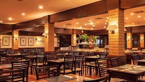 A restaurant with brick pillars, wooden tables, and chairs.