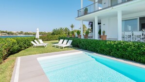 Area piscina moderna con lettini e vista sul mare.