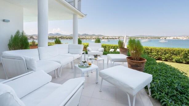 Una terrazza con mobili bianchi, vista sul mare e piante in vaso.