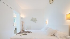 Una camera da letto minimalista con un letto grande, comodini e una lampada a parete.