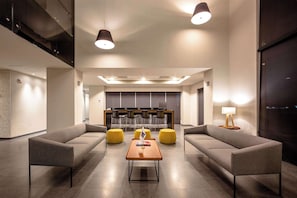 Un hall d’entrée moderne avec deux canapés, une table basse et un comptoir de réception avec des chaises.
