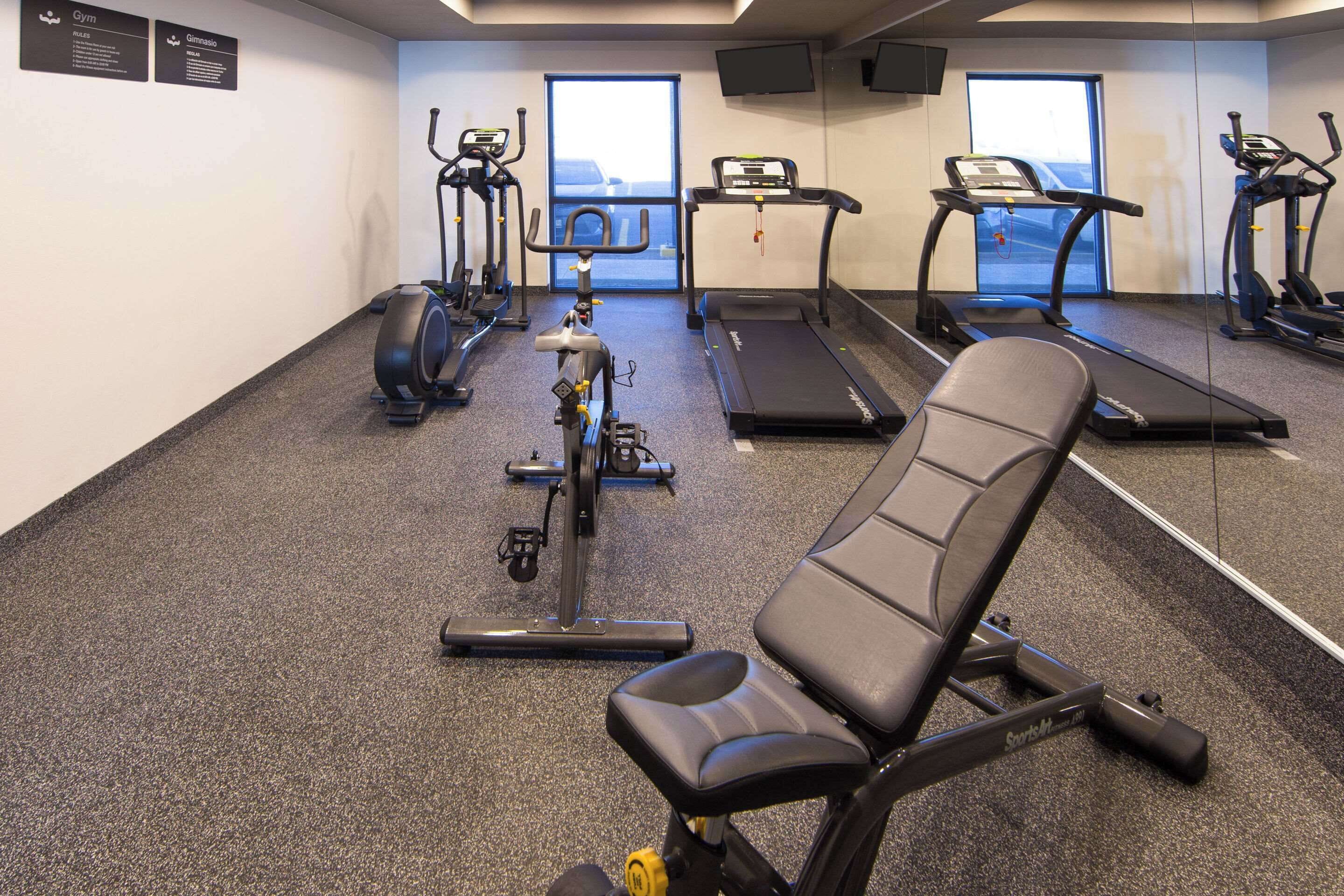 Ett gym med olika typer av träningsutrustning, inklusive löpband, motionscyklar och en roddmaskin.
