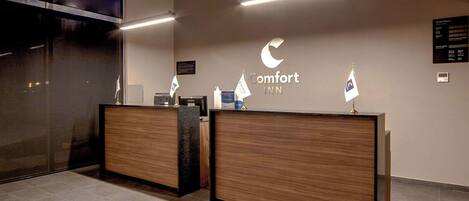A reception desk with a wooden finish and a sign reading "Comfort INN".