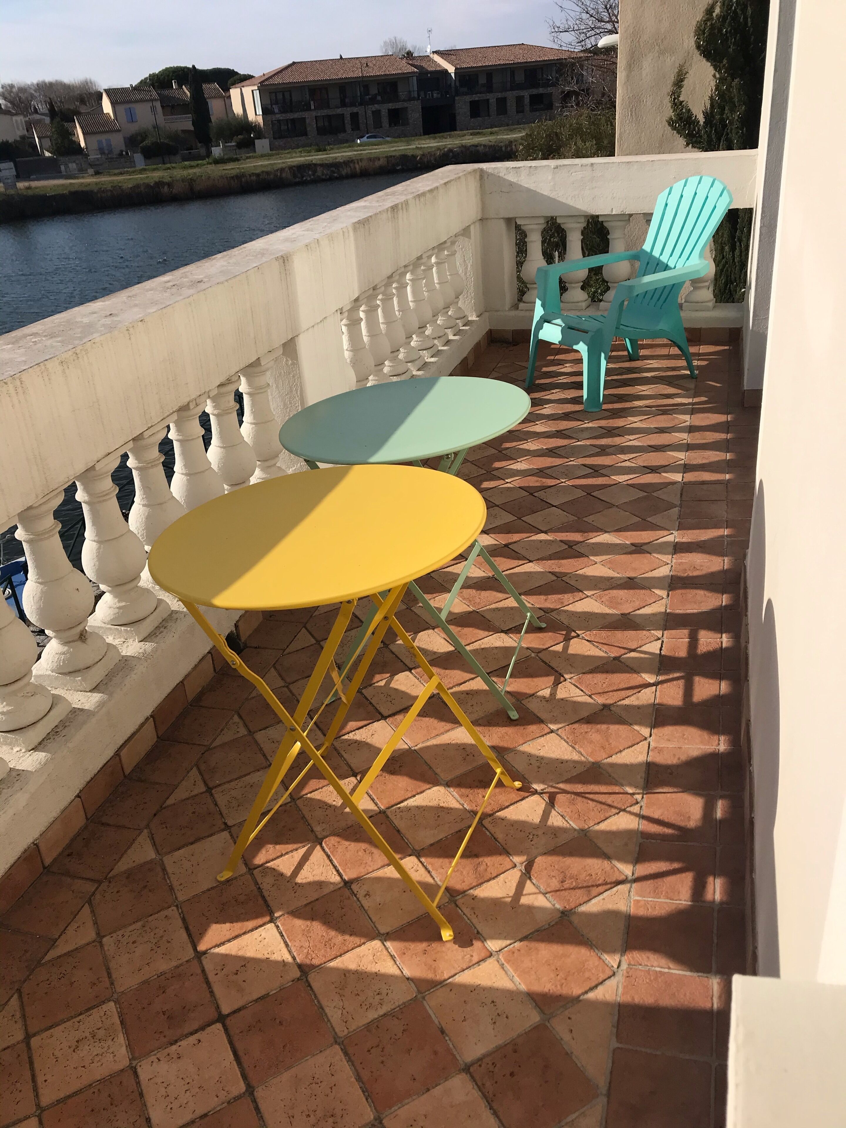 A terrace with a tiled floor, a white balustrade, and two tables with chairs.