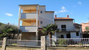 A two-story building with a balcony on the second floor, a stone fence in front, and a clear blue sky. - SENA Studio with Balcony 1 (Rovinj)