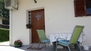 A small outdoor seating area with two chairs and a table, a wooden door, and a potted plant. - ANTOLOVIC Studio with Terrace (Rovinj)
