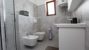 A modern bathroom with a glass shower enclosure, a bidet, a toilet, and a sink with a marble countertop. - ANTOLOVIC Studio with Terrace (Rovinj)