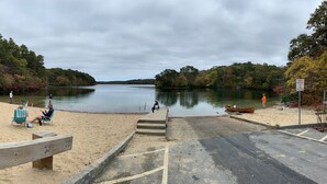 A beach with a sandy shore, a wooden bench, and a boat on the water.