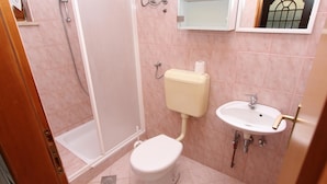 Een kleine badkamer met toilet, wastafel en douche.