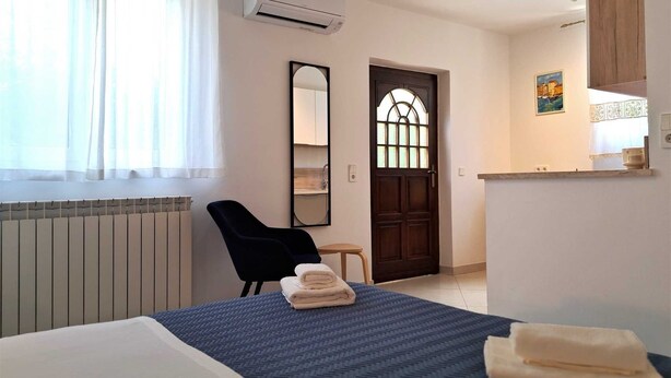 Hotelkamer met een bed, een stoel, een bureau, een spiegel, een deur en een airconditioning.