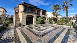 Una casa de dos pisos con fachada de piedra, un balcón y un patio empedrado.