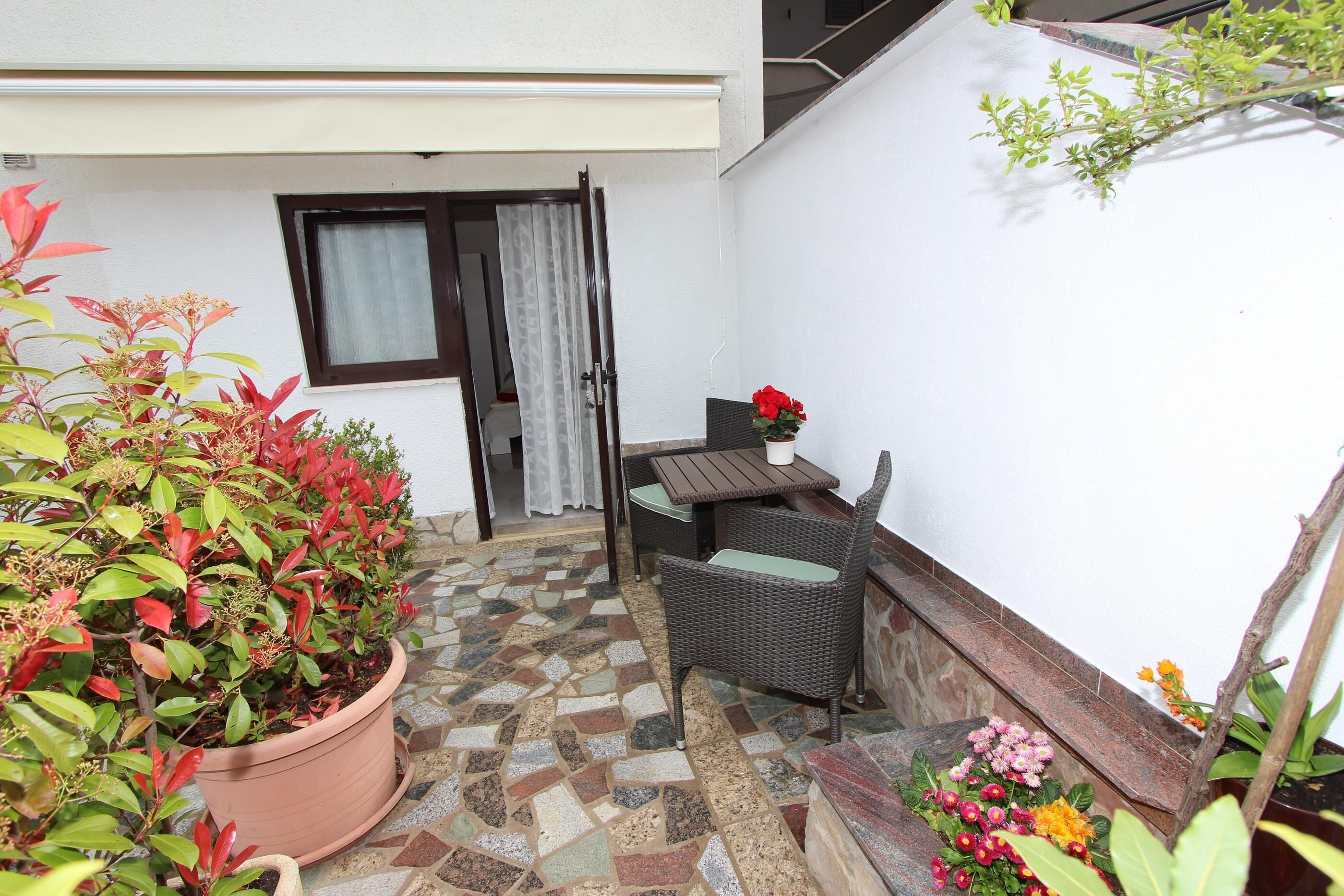 A patio area with a potted plant, a wicker chair, and a small table.