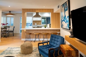 Una cocina moderna con una isla central, detalles de madera y un comedor con sillas y una mesa.