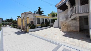 Una calle residencial con dos casas, una de fachada de piedra y la otra con paredes amarillas.