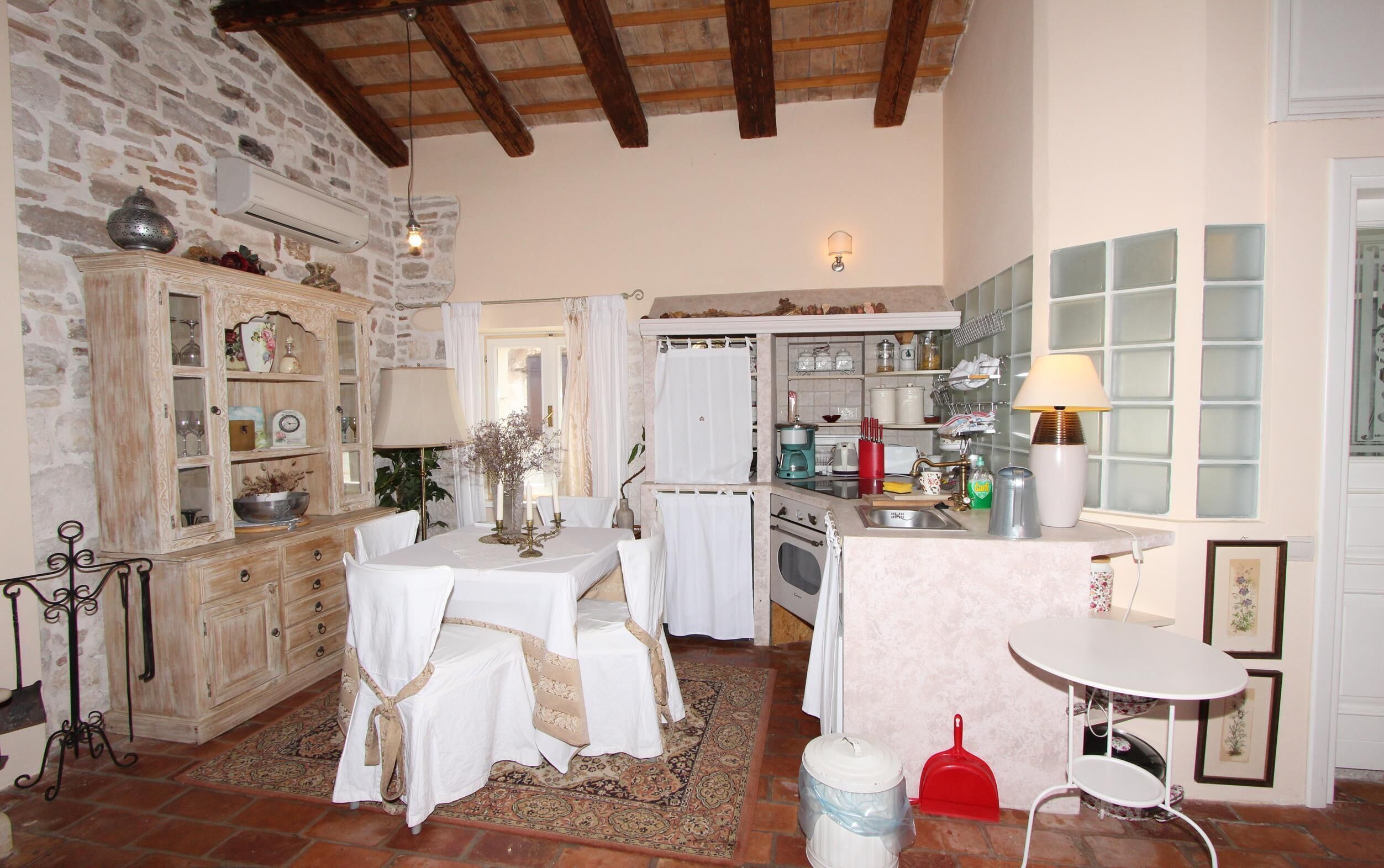 A rustic kitchen with a stone wall, wooden beams, and a tiled backsplash.