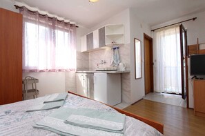 Ein Schlafzimmer mit Bett, einer kleinen Küchenzeile, einem Fernseher und einem Badezimmer.