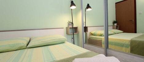 A hotel room with two beds, a large mirror, and a wooden door.