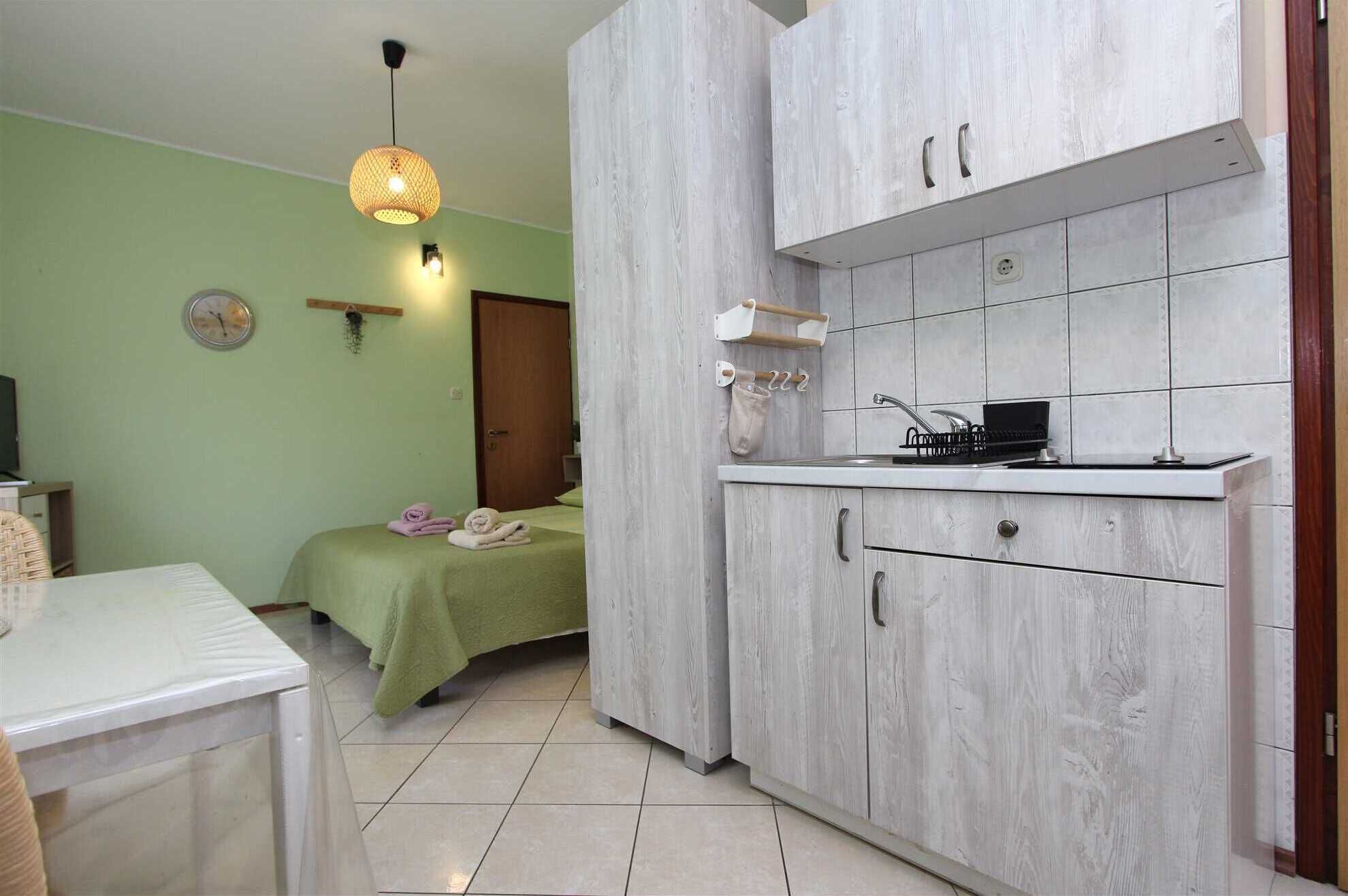 Una habitación compacta con cama, una pequeña kitchenette y zona de comedor.