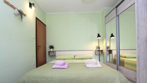 Een slaapkamer met een bed, twee nachtkastjes, een spiegel en een deur.